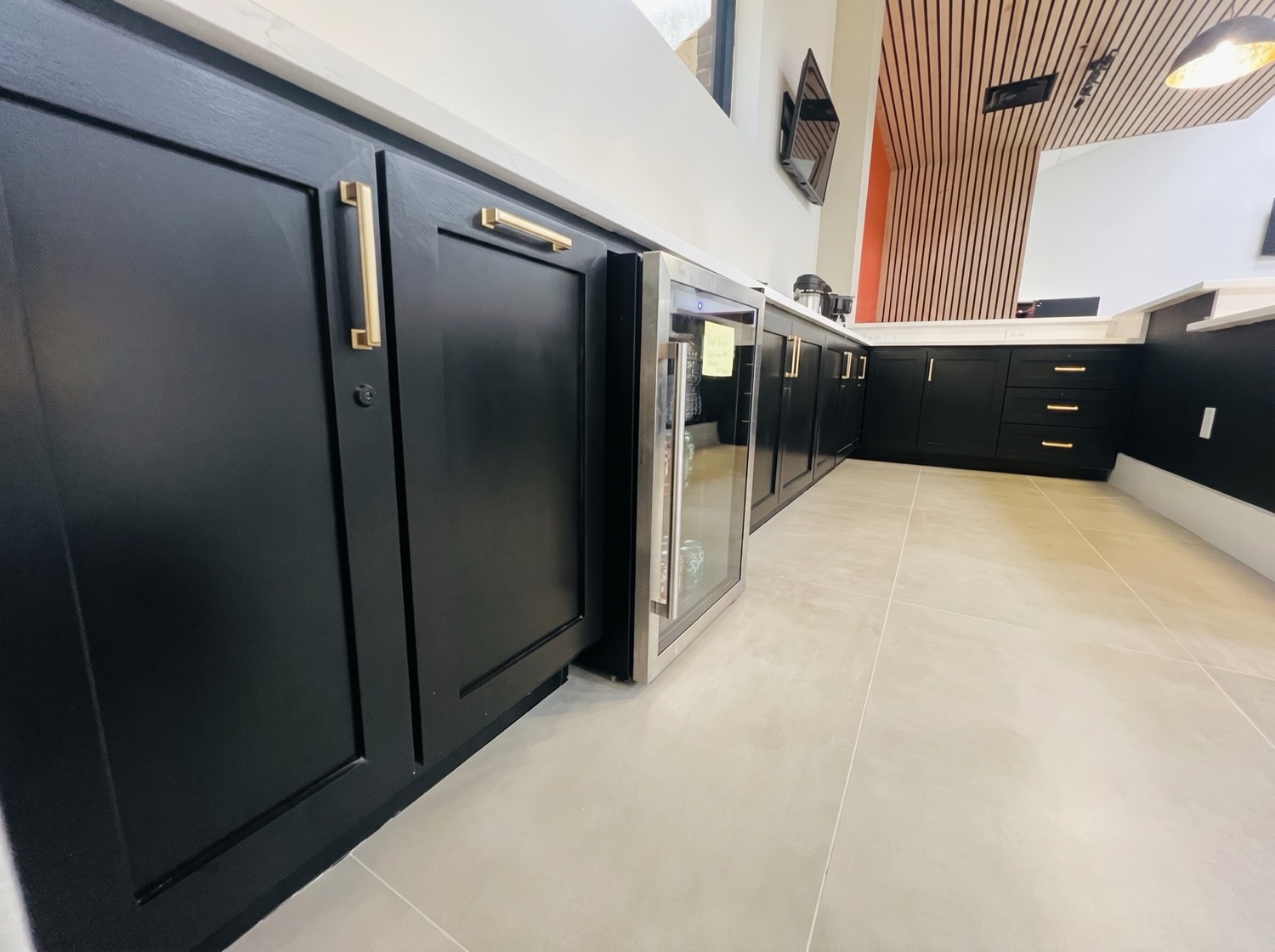 Commercial bar cabinetry with matte black cabinets, gold hardware, and an under-counter beverage cooler