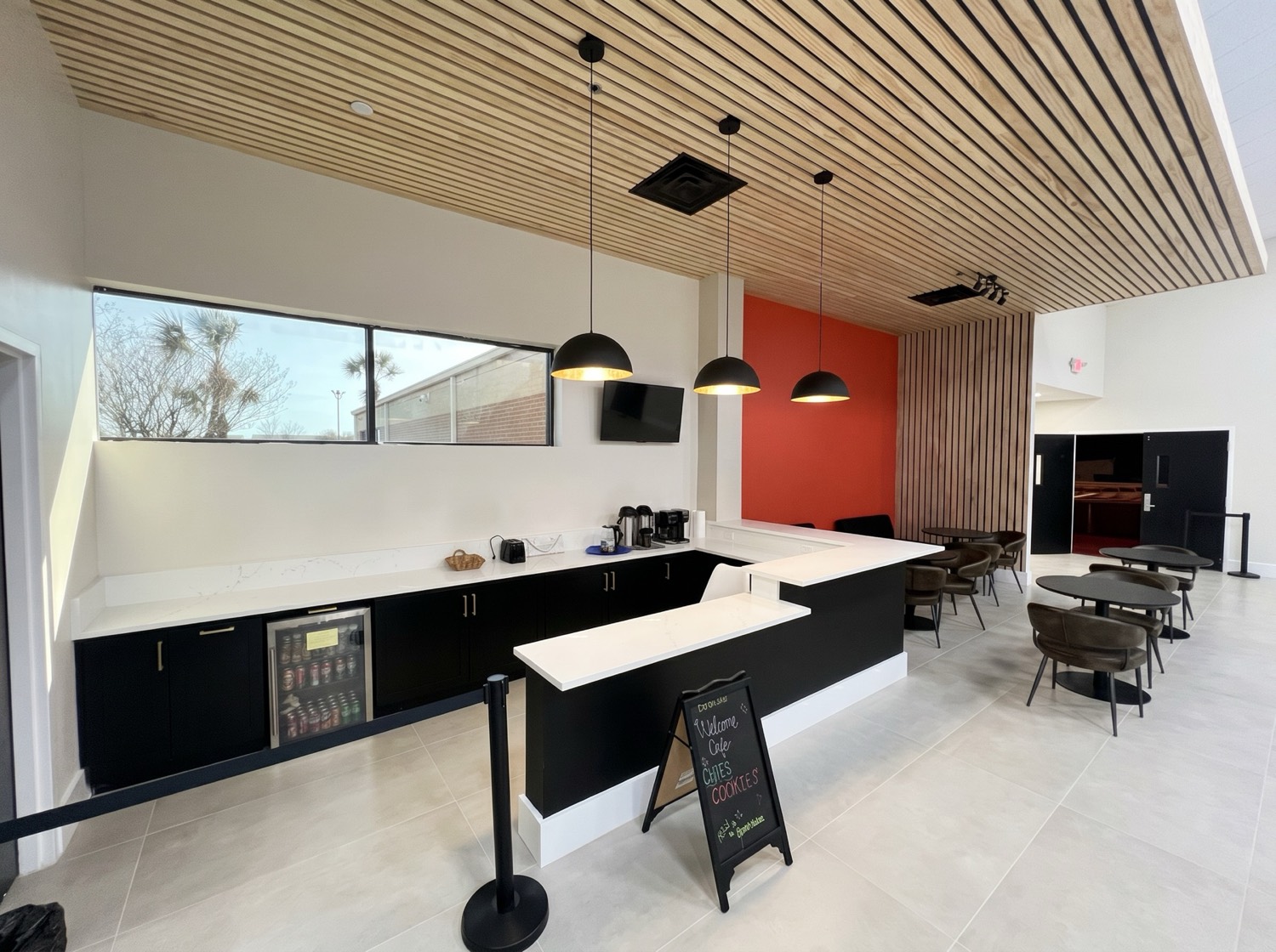 Modern commercial cafe build-out with black cabinetry, pendant lighting, and a wood slat ceiling