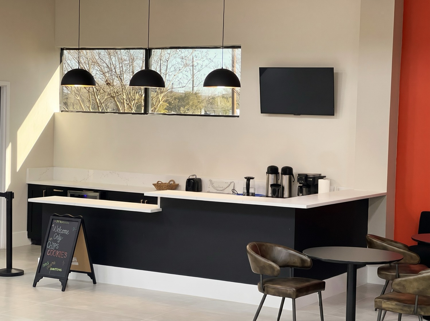 Commercial cafe service bar with black cabinetry, white counters, and pendant lights