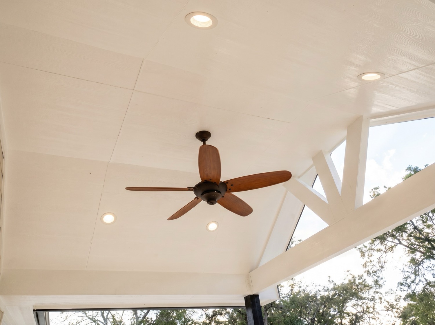Covered patio ceiling detail with warm wood tones, a ceiling fan, and built-in lighting