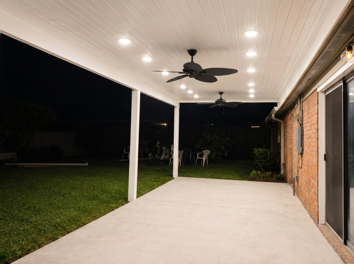 Covered backyard patio addition with recessed lighting and ceiling fans at night