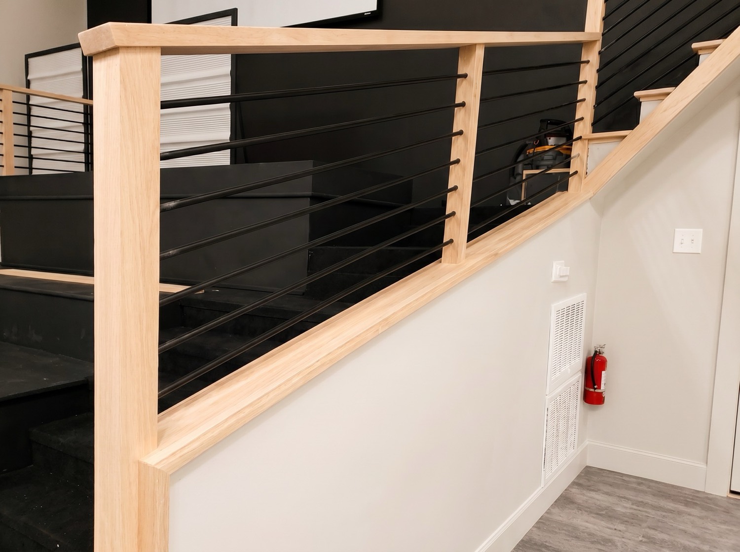 Custom stair railing with natural wood posts and black horizontal cable detail