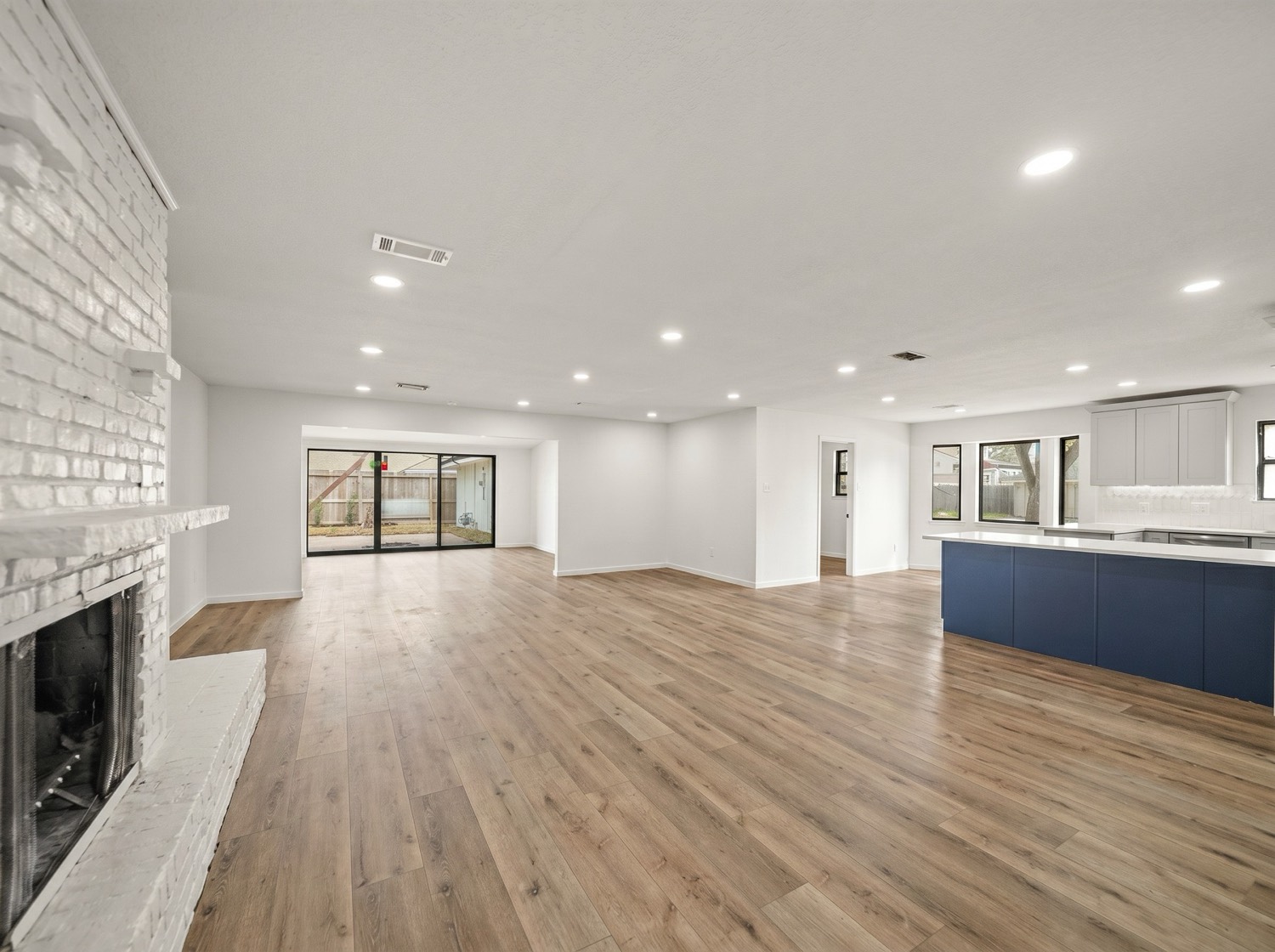 Open-concept living area after electrical lighting upgrades, with the existing fireplace and flooring visible in the room